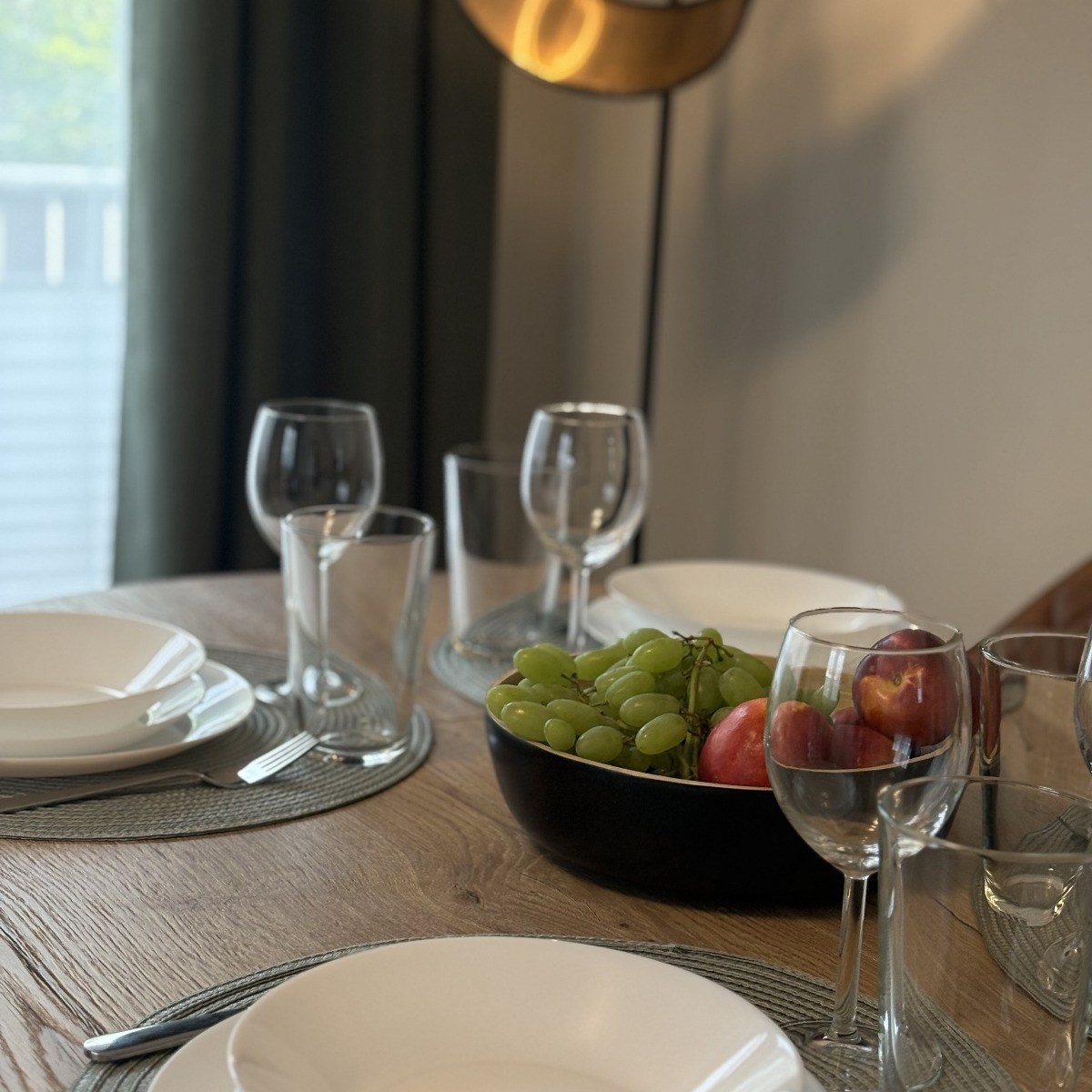 schön gedeckter Esstisch mit weißen Tellern, Wasser- und Weingläsern